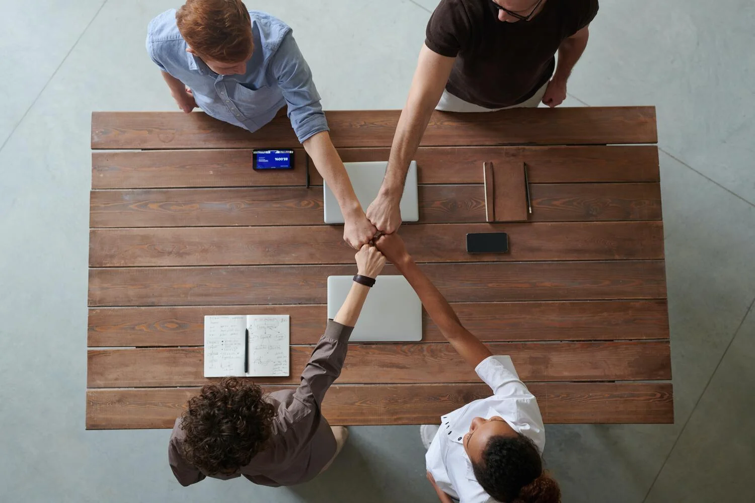 puños del equipo unidos sobre mesa de madera
